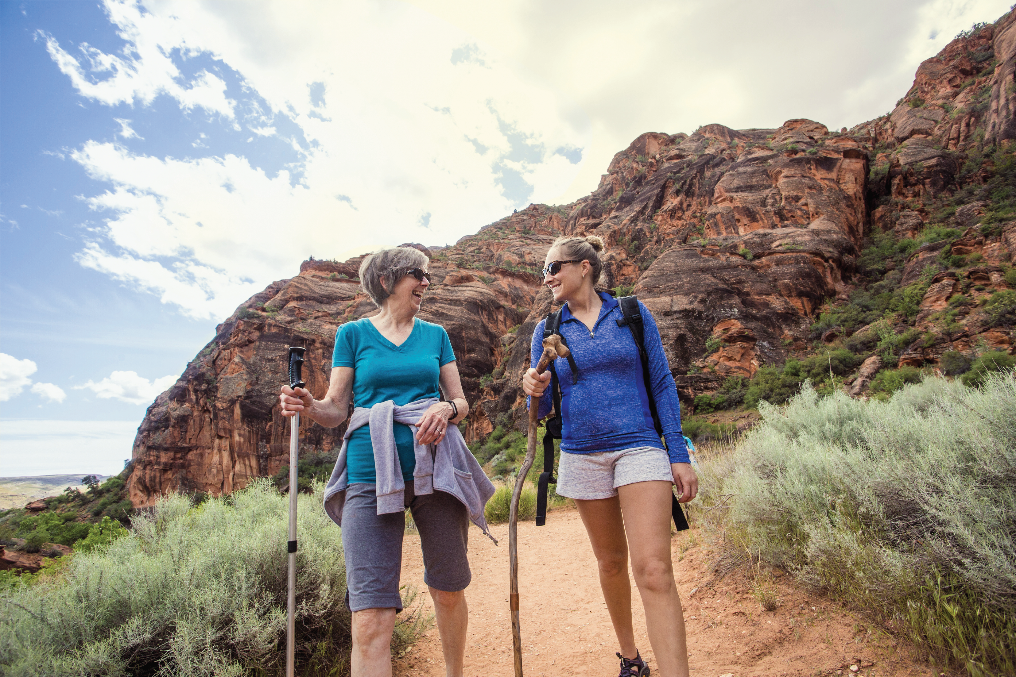 2 ladies holding walking sticks while hiking