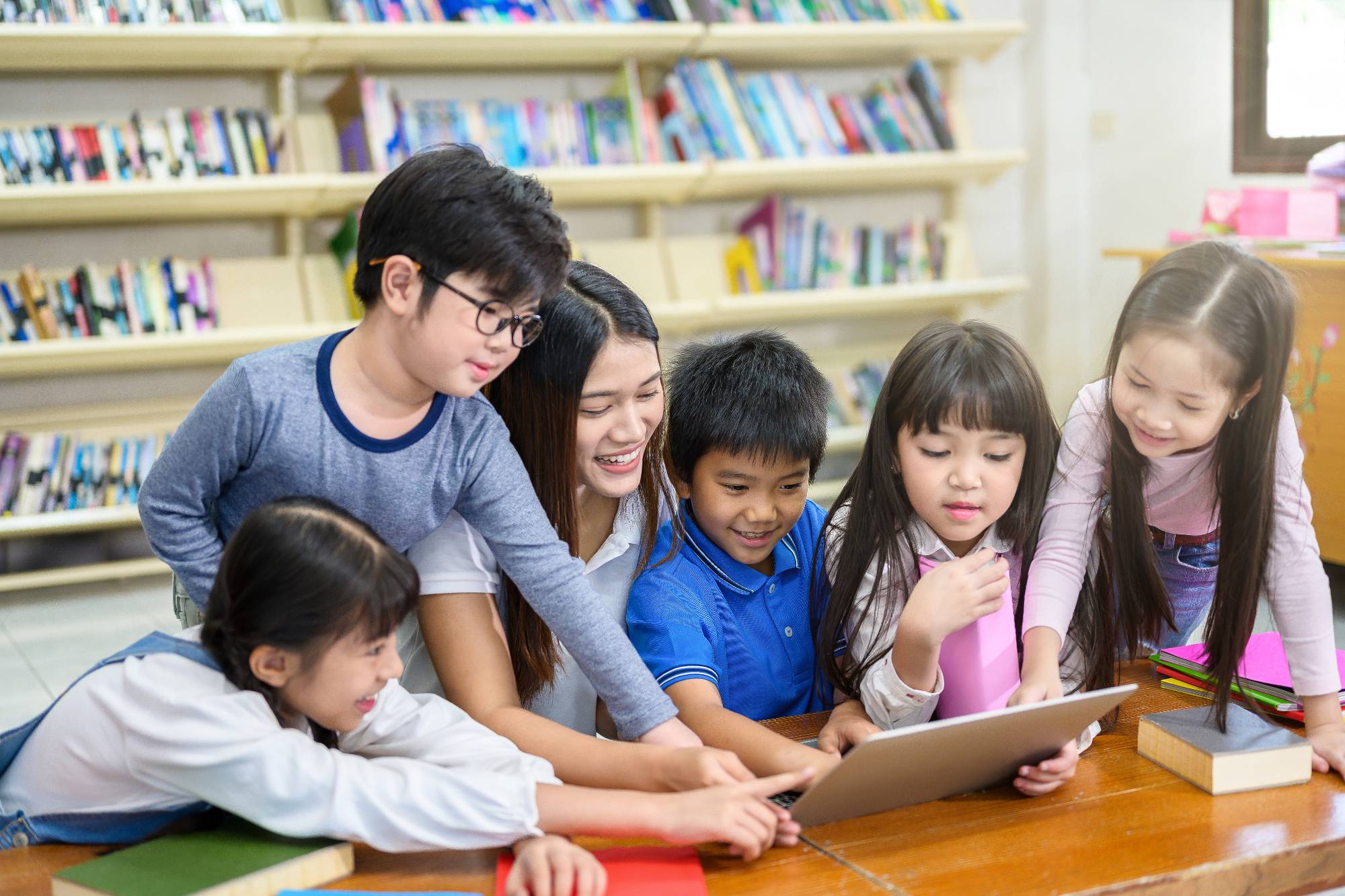 Students and the teacher looking at the laptop