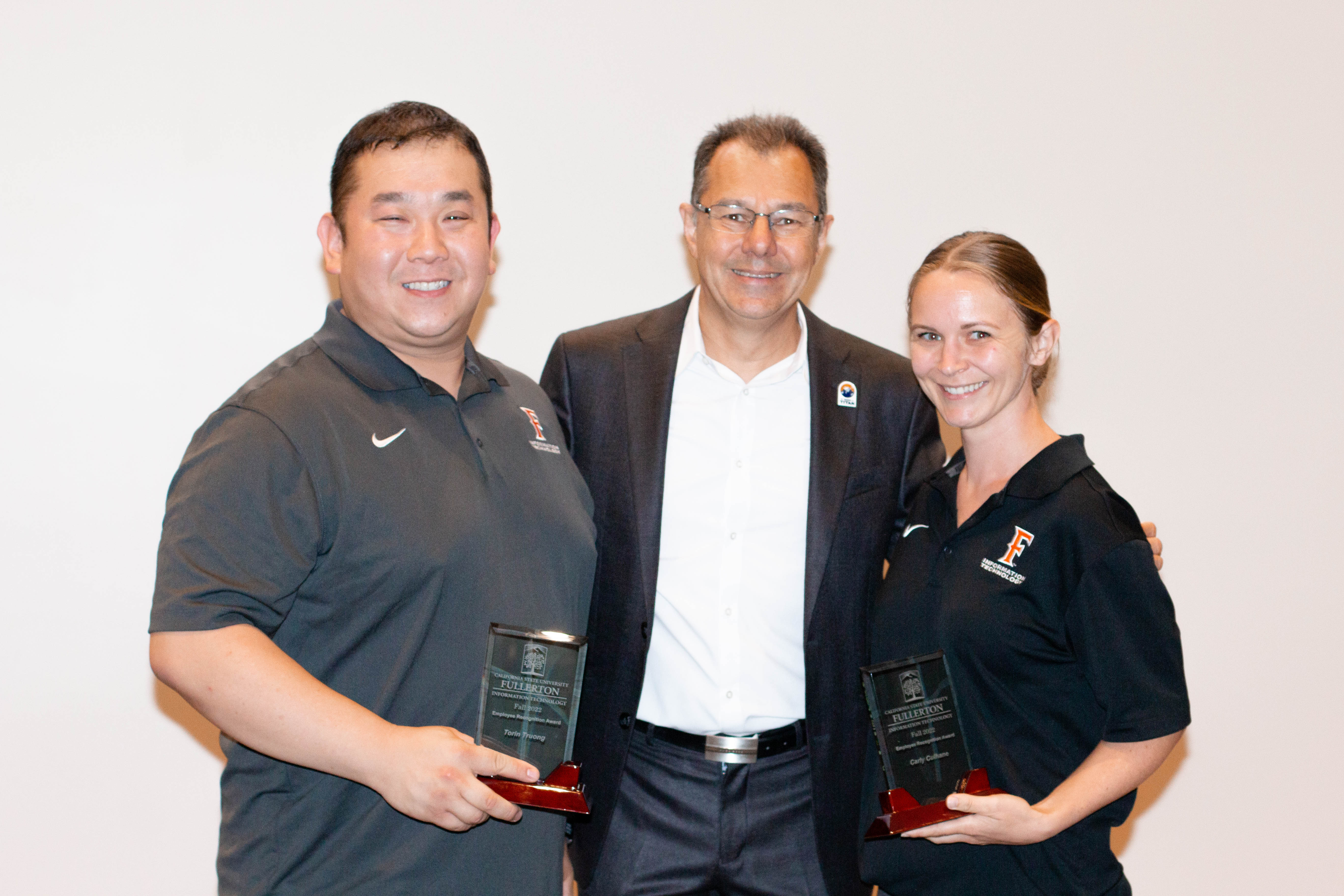 Vice President Amir Dabirian congratulates award winners Torin Truong and Carly Culhane on winning the employee recognition for Fall 2022. 